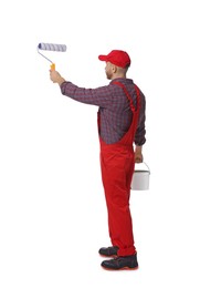 Professional painter with roller and bucket of paint working on white background