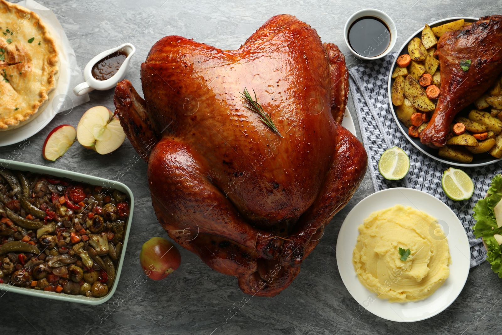 Photo of Whole baked turkey and other dishes served on grey table, flat lay