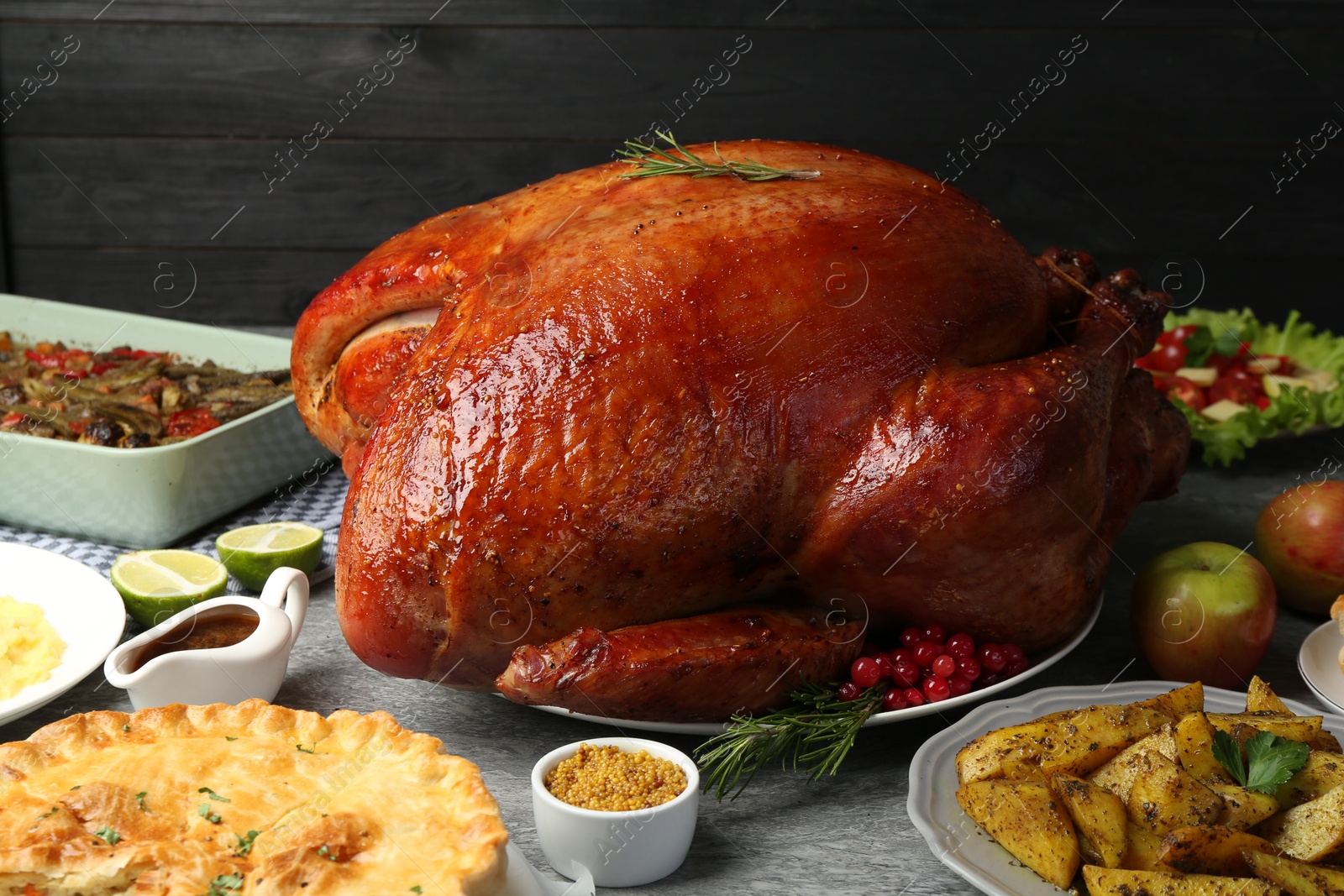 Photo of Whole baked turkey and other dishes served on grey table, closeup