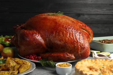 Photo of Whole baked turkey and other dishes served on grey table, closeup