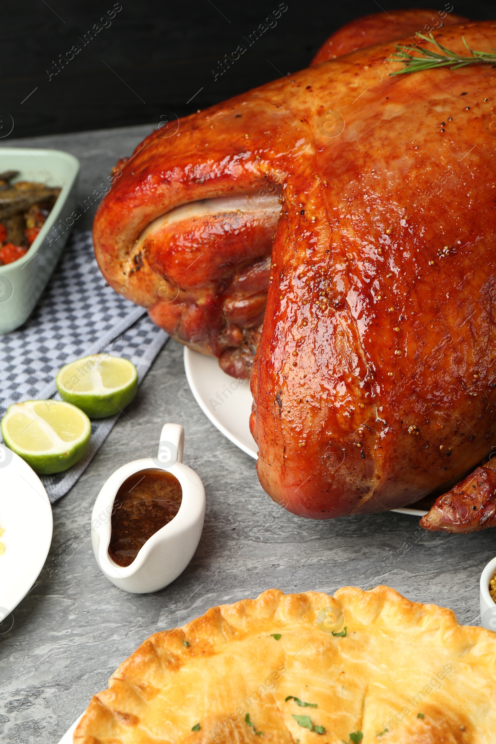 Photo of Whole baked turkey and other dishes served on grey table, closeup