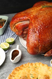 Photo of Whole baked turkey and other dishes served on grey table, closeup