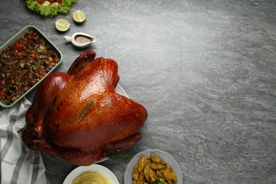 Photo of Whole baked turkey and other dishes served on grey table, flat lay. Space for text