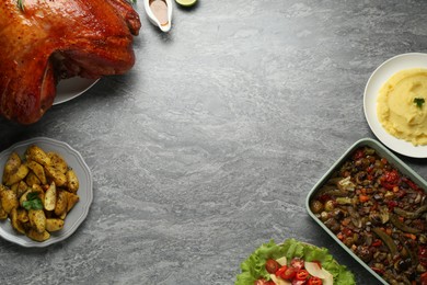 Photo of Whole baked turkey and other dishes served on grey table, flat lay. Space for text