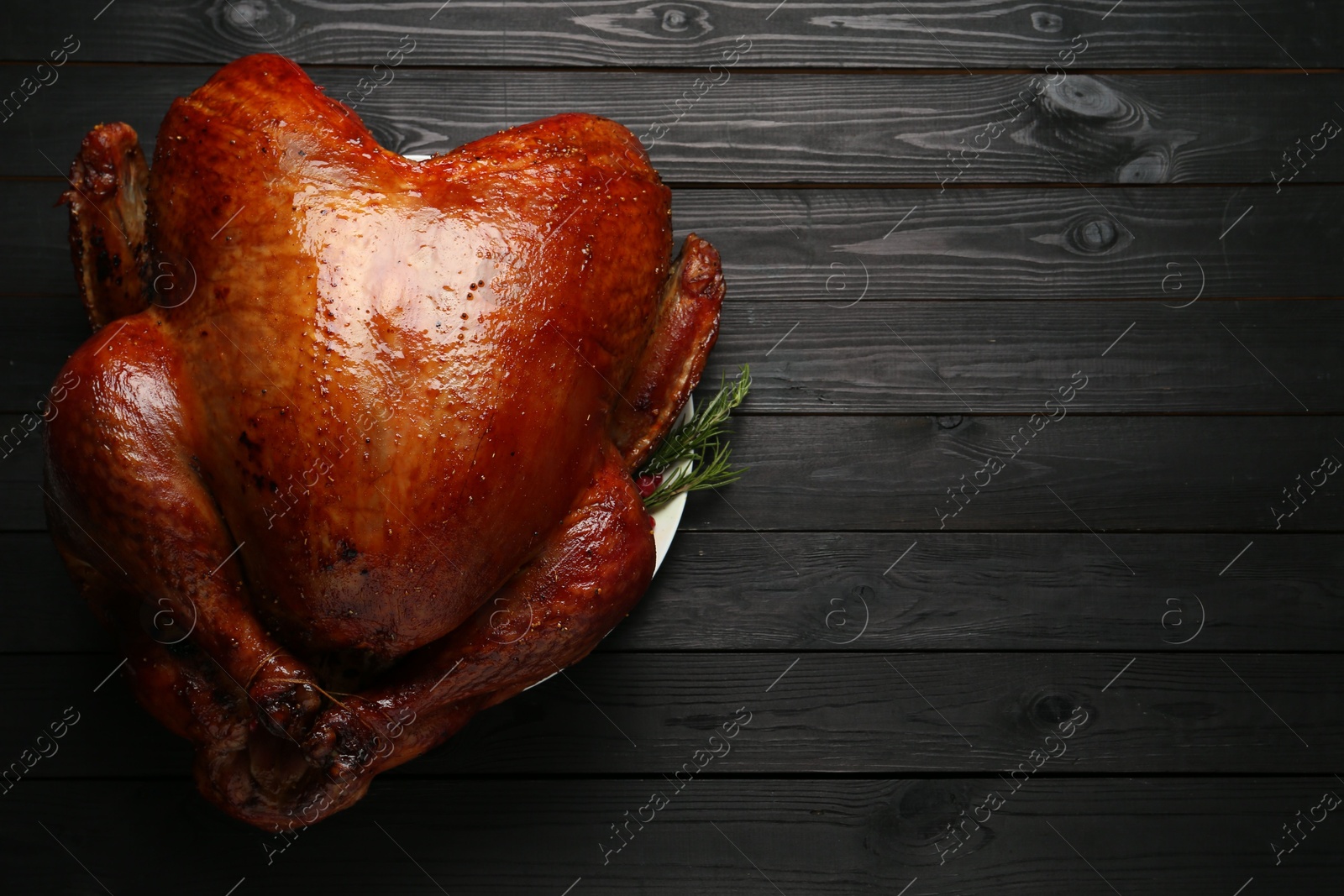 Photo of Whole baked turkey on black wooden table, top view. Space for text