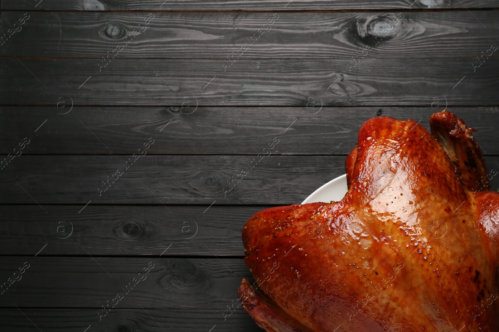 Photo of Whole baked turkey on black wooden table, top view. Space for text