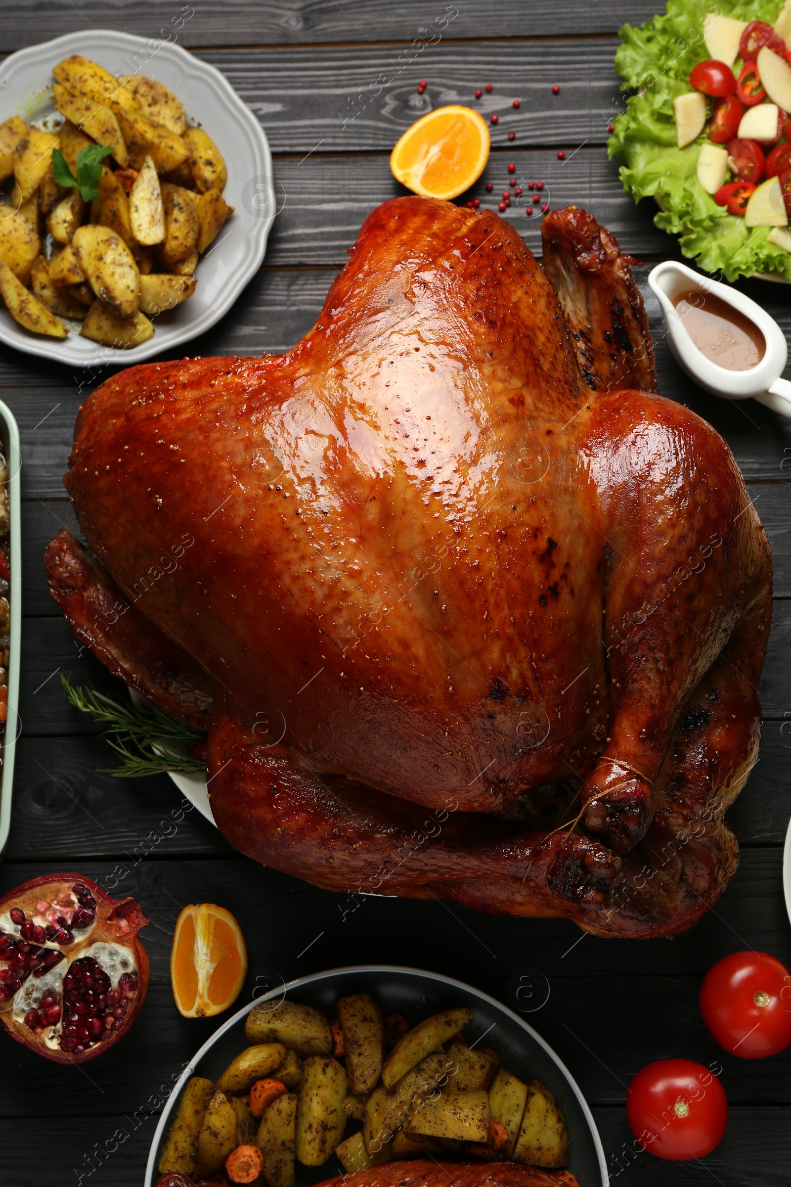 Whole baked turkey and other dishes served on black wooden table, flat lay Photo of Whole baked turkey and other dishes served on black wooden table, flat lay