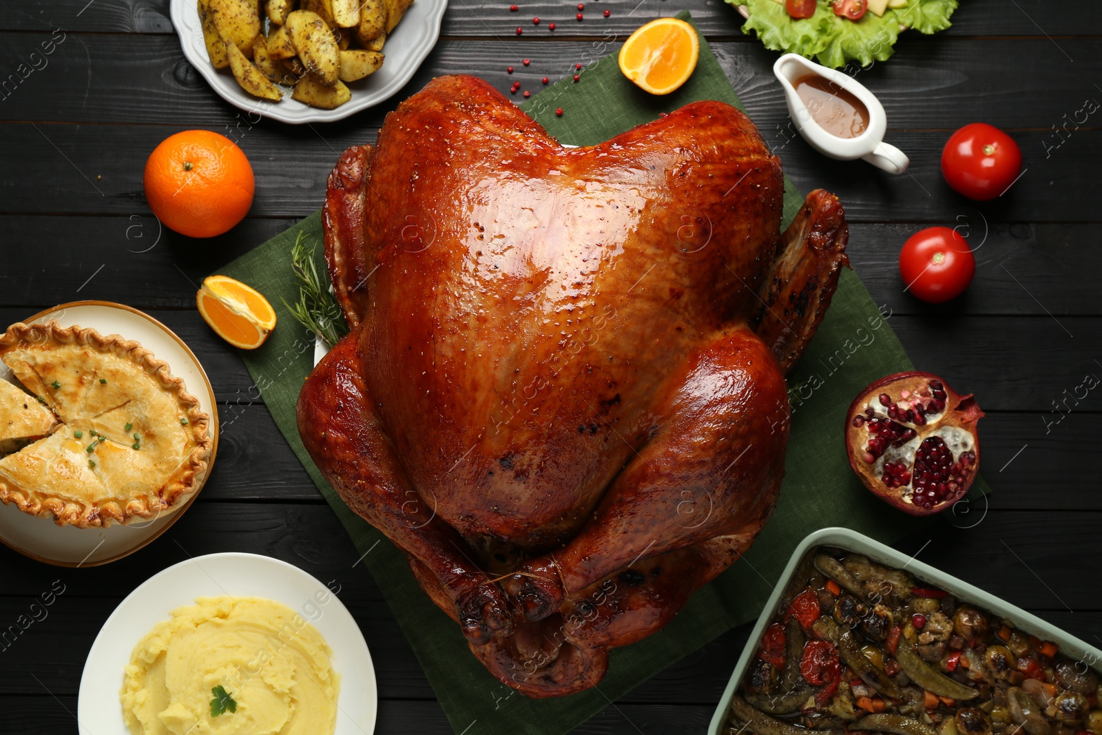 Photo of Whole baked turkey and other dishes served on black wooden table, flat lay