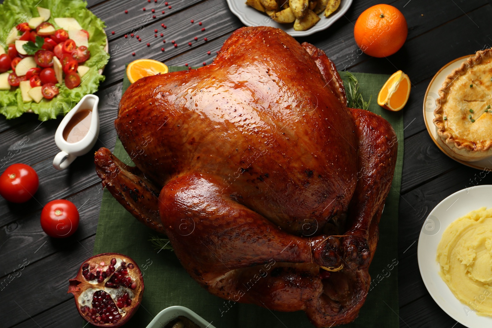 Photo of Whole baked turkey and other dishes served on black wooden table, above view