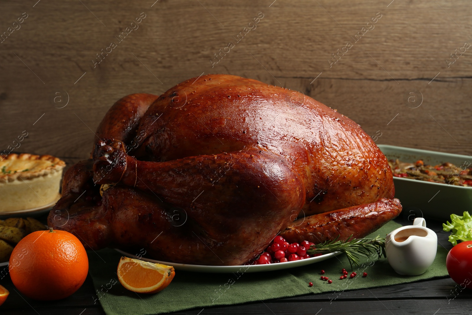 Photo of Whole baked turkey and other dishes served on black wooden table