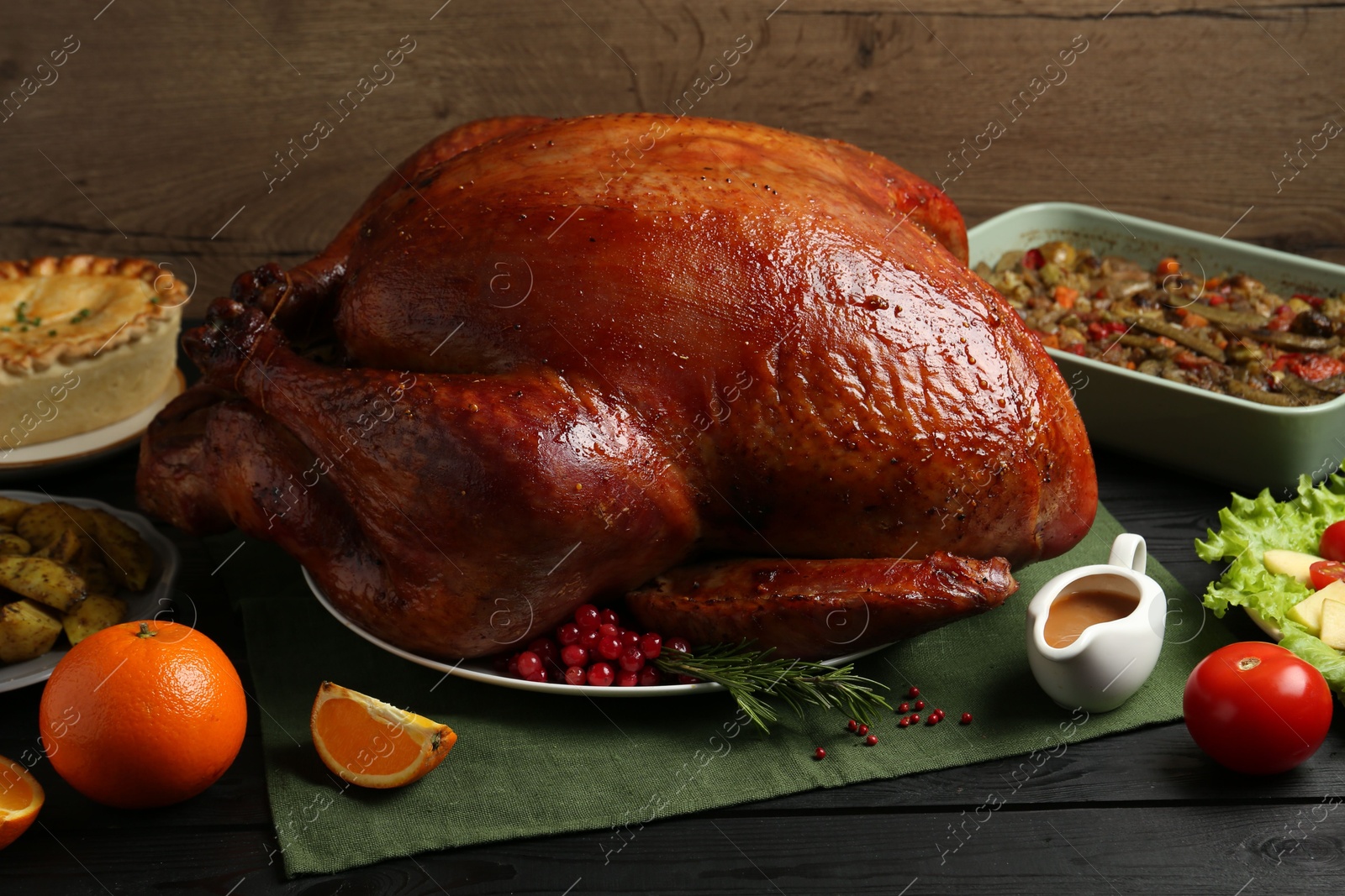 Photo of Whole baked turkey and other dishes served on black wooden table