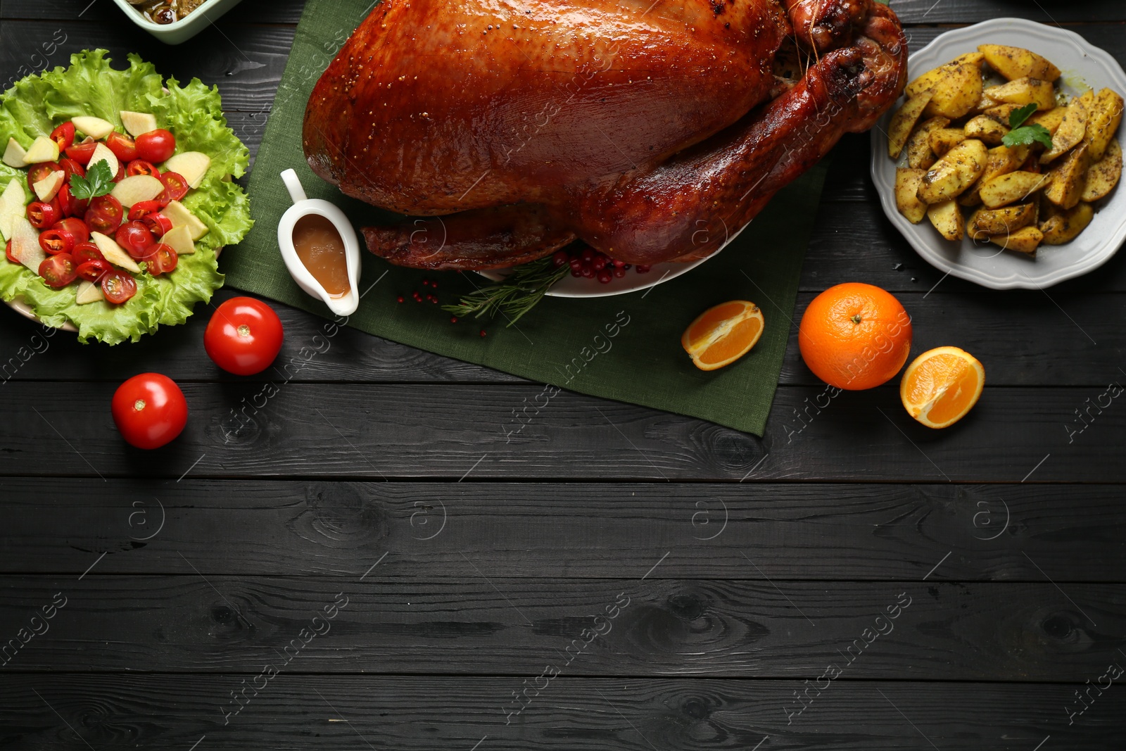 Photo of Whole baked turkey and other dishes served on black wooden table, flat lay. Space for text