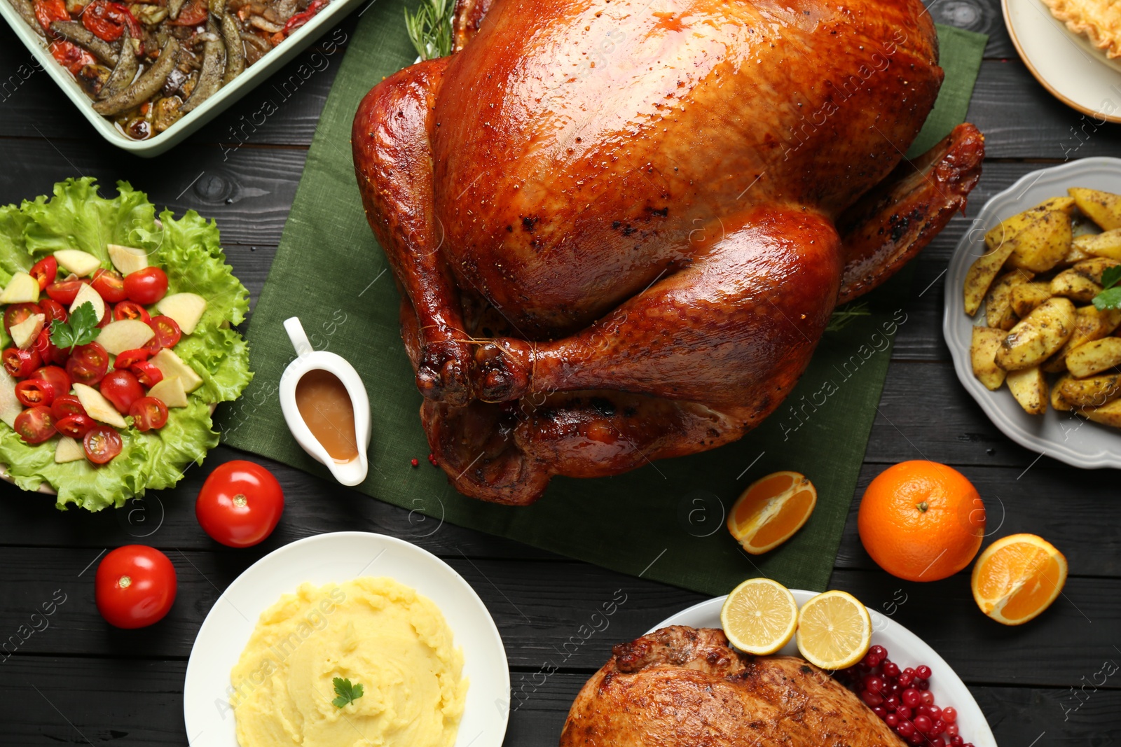 Photo of Whole baked turkey and other dishes served on black wooden table, flat lay