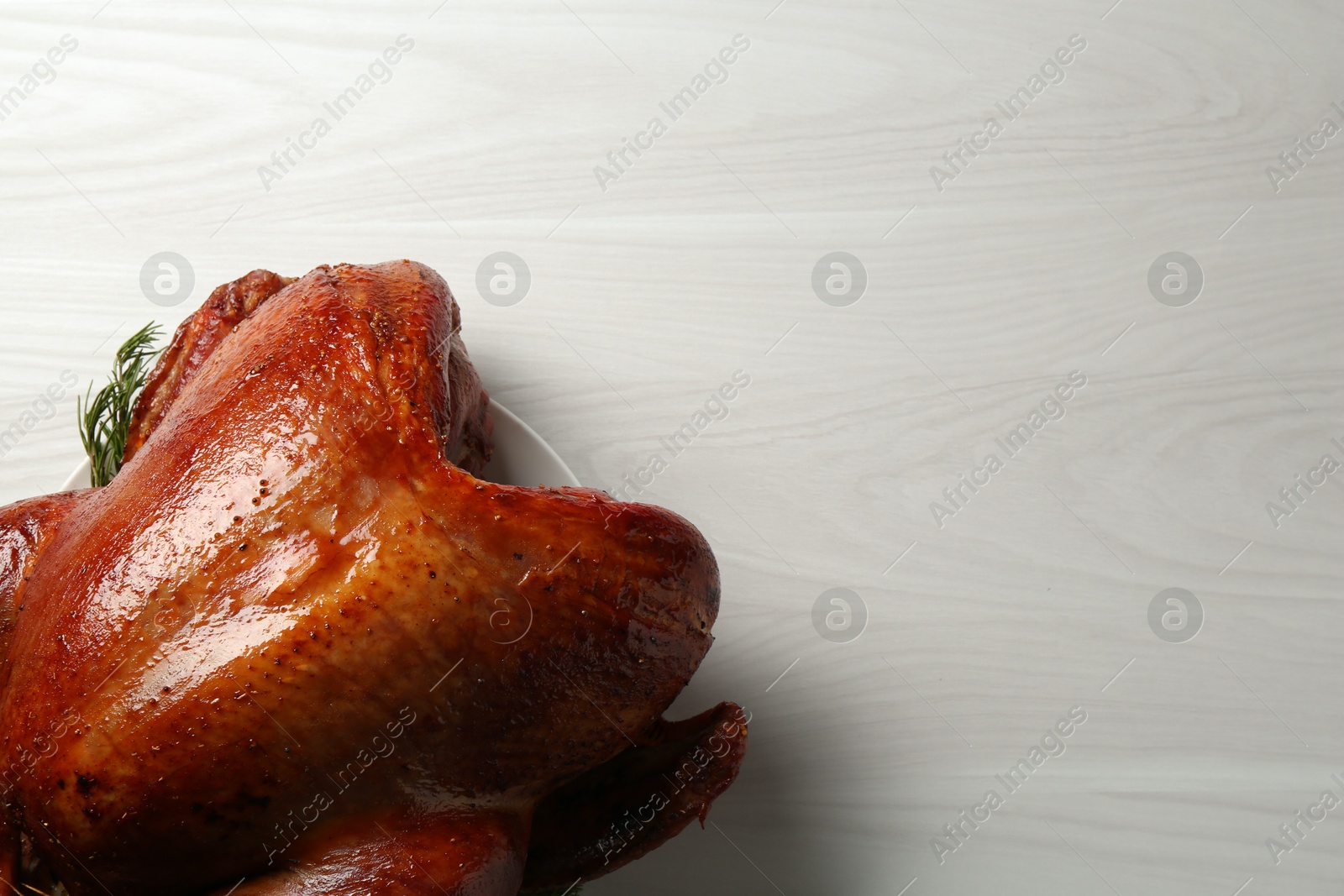 Photo of Whole baked turkey on light wooden table, top view. Space for text