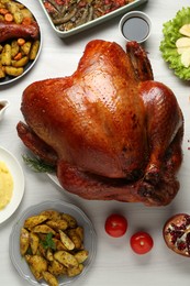 Photo of Whole baked turkey and other dishes served on light wooden table, flat lay