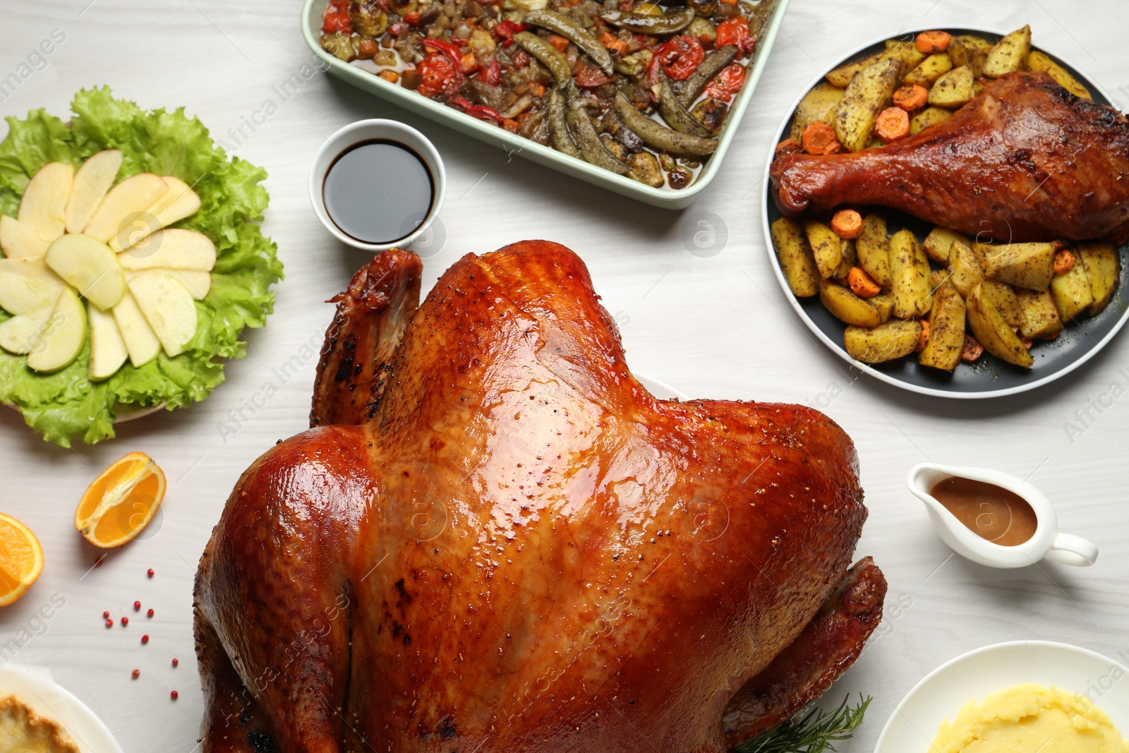 Photo of Whole baked turkey and other dishes served on light wooden table, flat lay