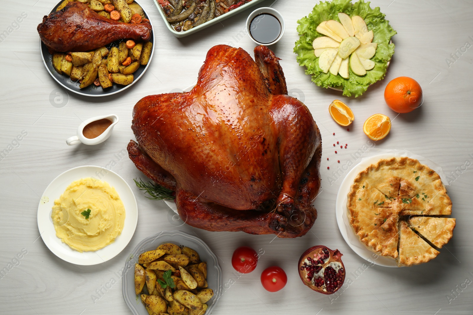 Photo of Whole baked turkey and other dishes served on light wooden table, flat lay