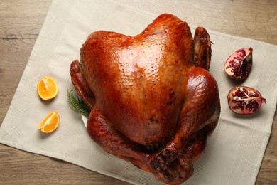 Photo of Whole baked turkey, orange and pomegranate slices on wooden table, flat lay