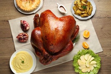 Photo of Whole baked turkey and other dishes served on wooden table, flat lay