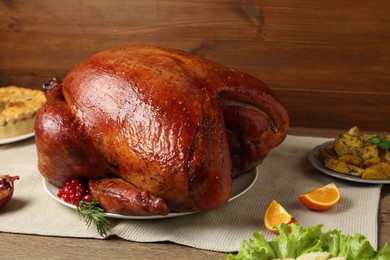 Photo of Whole baked turkey and other dishes served on wooden table