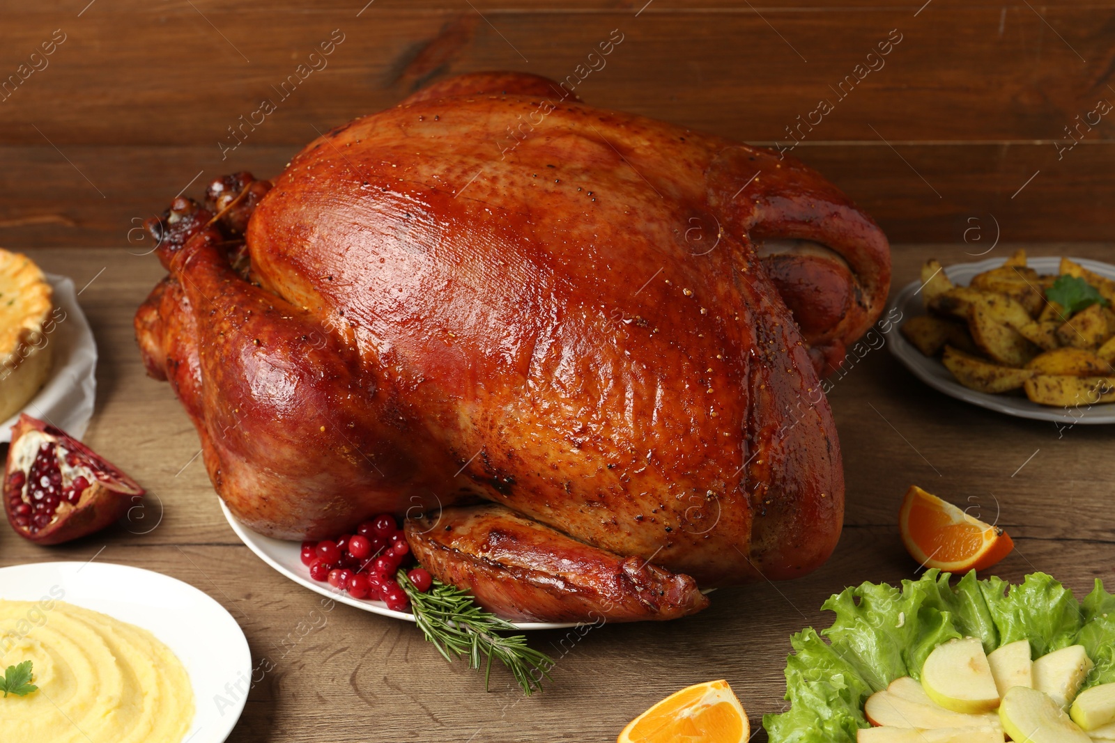 Photo of Whole baked turkey and other dishes served on wooden table, closeup