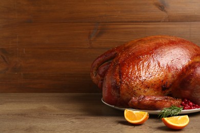 Photo of Whole baked turkey with cranberries, rosemary and orange slices on wooden table. Space for text