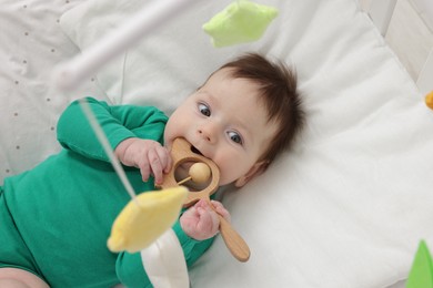 Photo of Cute little baby in crib with cot mobile at home, above view