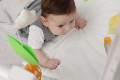 Photo of Cute little baby in crib with cot mobile at home