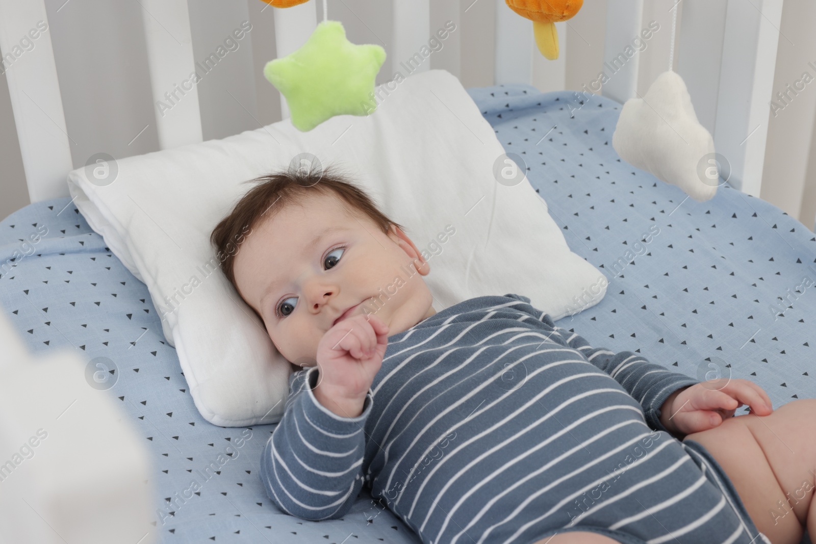 Photo of Cute little baby in crib with cot mobile at home