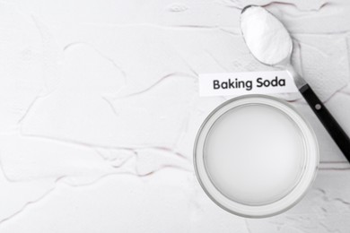 Photo of Glass with water and baking soda on white textured table, top view. Space for text