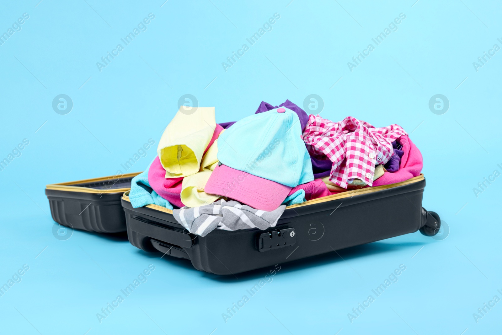 Photo of Packed suitcase full of clothes on light blue background