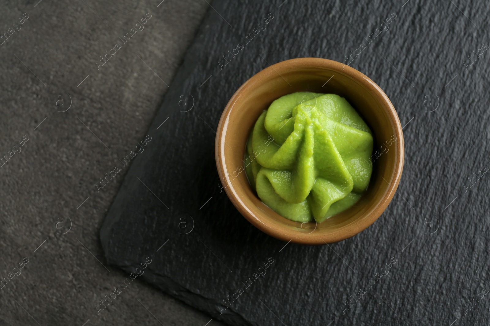 Photo of Hot wasabi paste in bowl on grey textured table, top view. Space for text