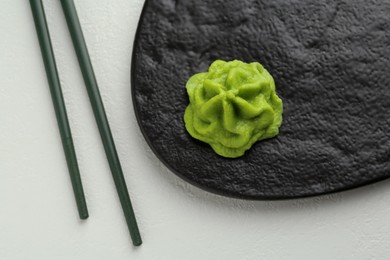 Photo of Slate board with hot wasabi paste and chopsticks on light textured table, top view