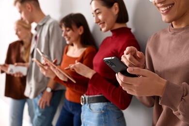 Photo of Group of people using different gadgets near light wall indoors. Modern technology