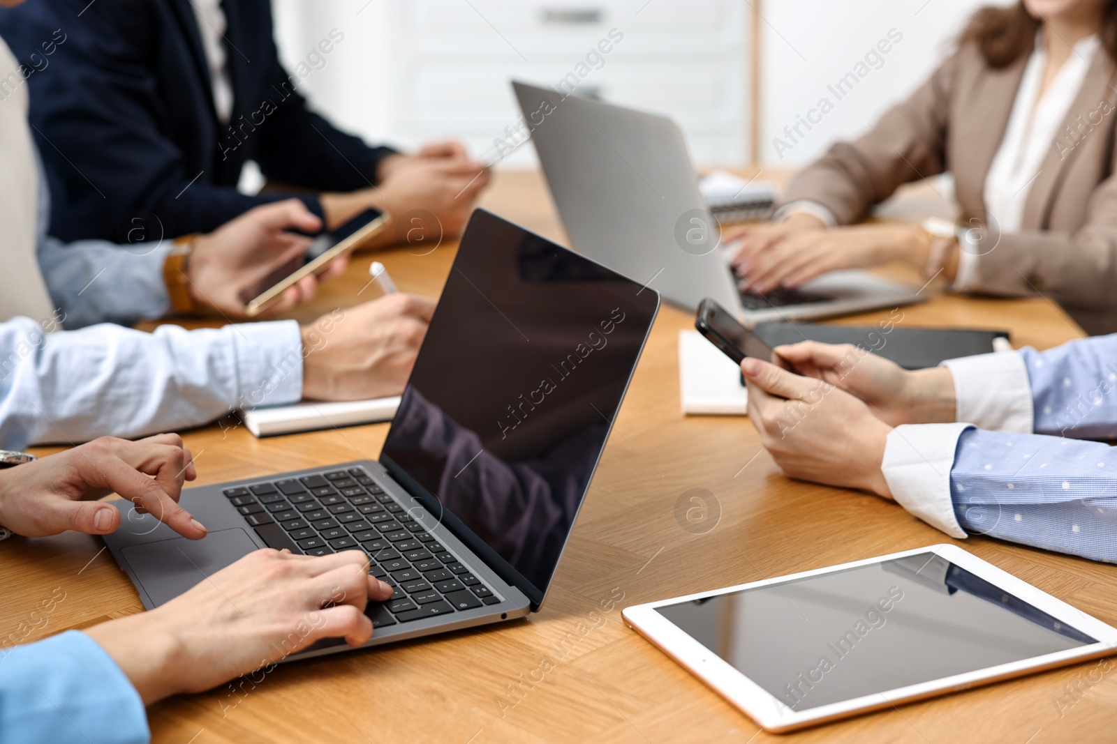 Photo of Group of people using different gadgets at wooden table in office, closeup. Modern technology