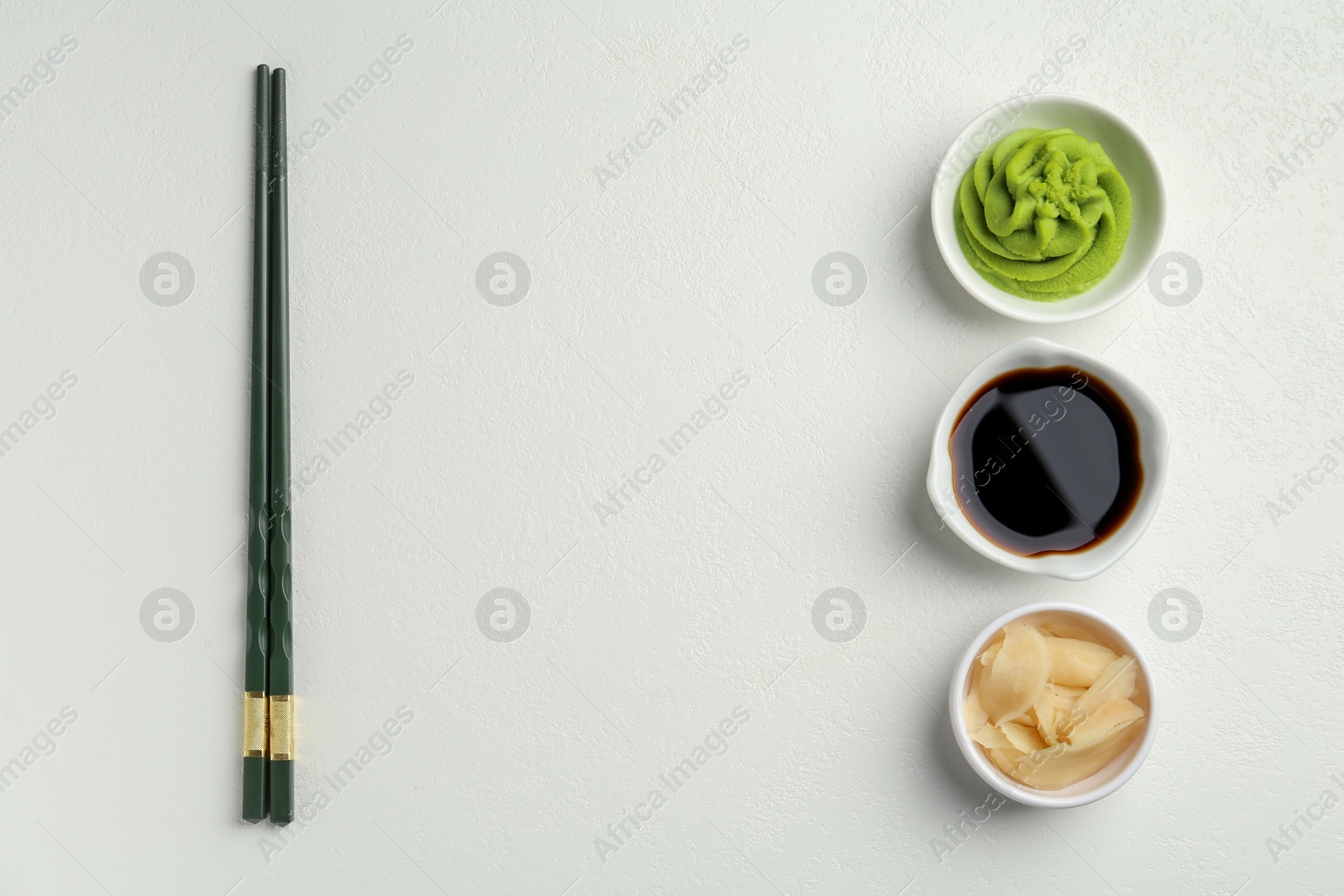 Photo of Hot wasabi paste, soy sauce, ginger and chopsticks on light textured table, flat lay. Space for text