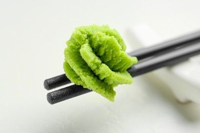 Photo of Chopsticks with hot wasabi paste on light table, closeup