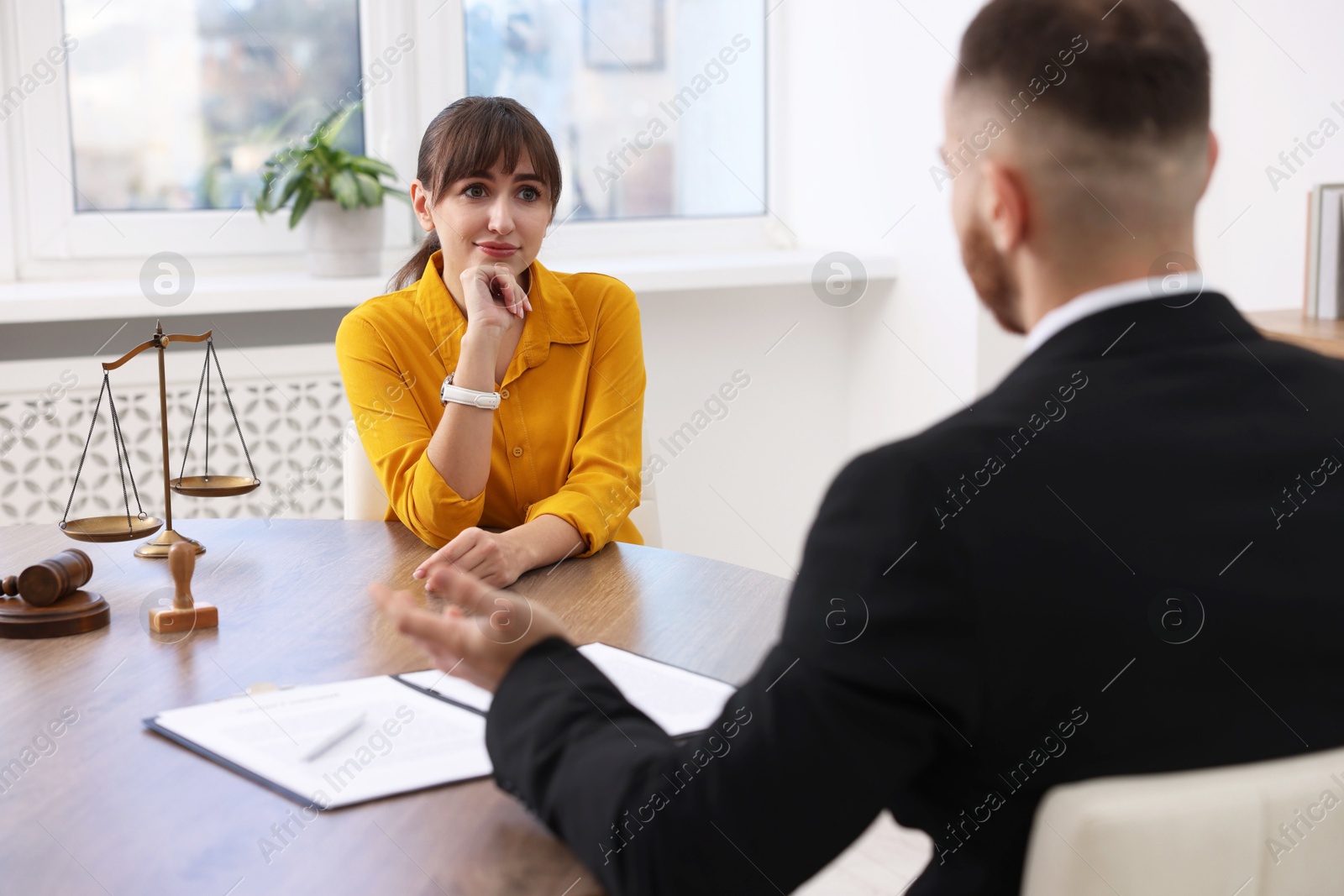 Photo of Woman having meeting with professional lawyer at wooden desk indoors