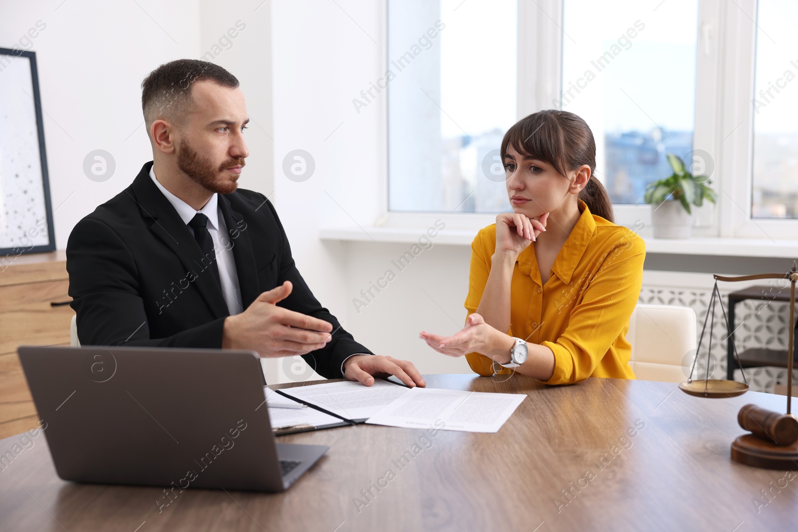 Photo of Woman having meeting with professional lawyer at wooden desk indoors