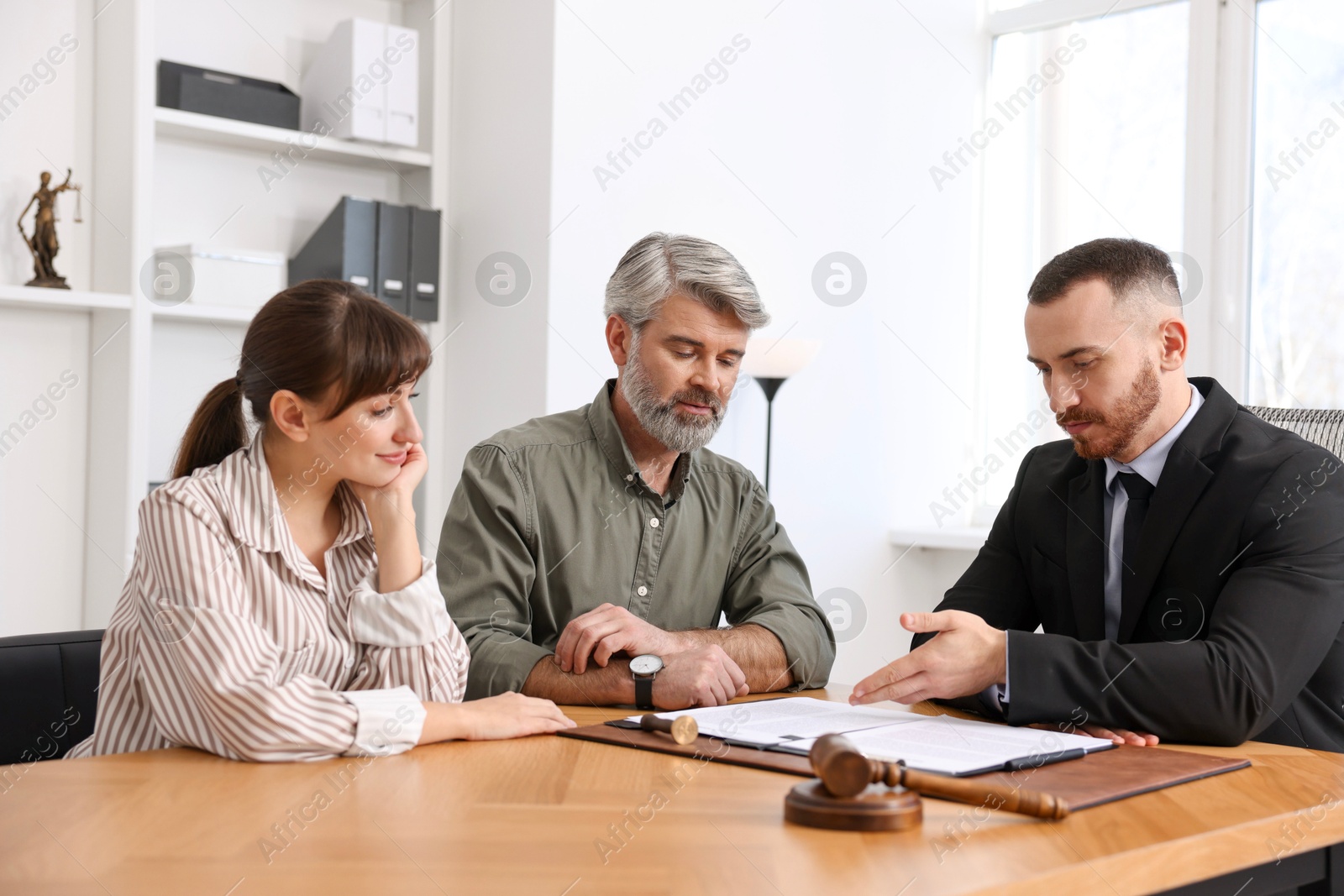 Photo of Couple having meeting with professional lawyer at wooden desk indoors