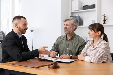 Couple having meeting with professional lawyer at wooden desk indoors