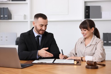 Photo of Client signing notarial paperwork during meeting with lawyer at wooden desk indoors