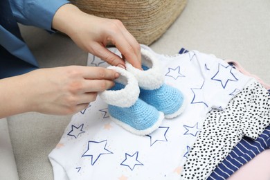 Photo of Woman with baby booties on sofa at home, closeup