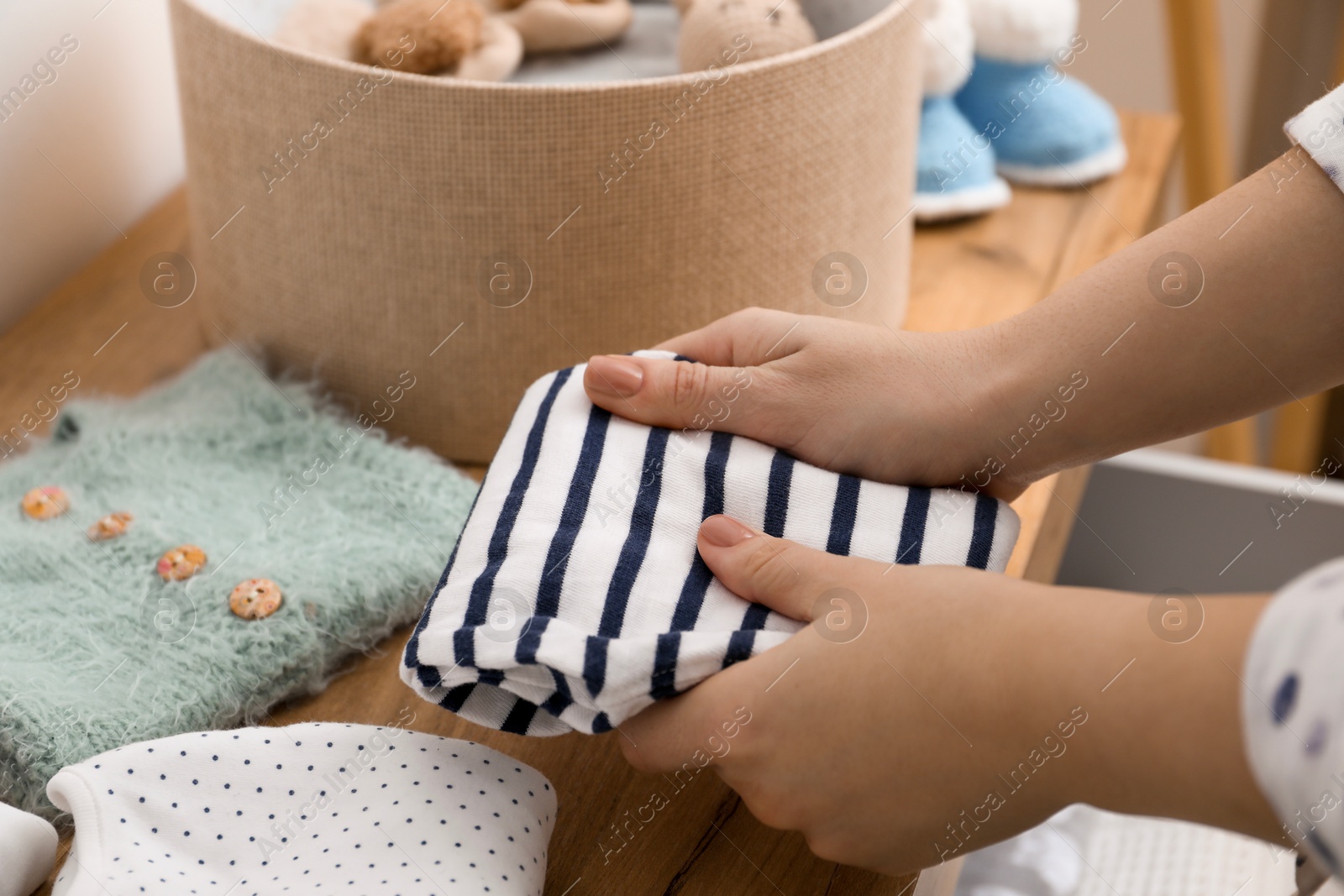 Photo of Woman with baby clothes at home, closeup