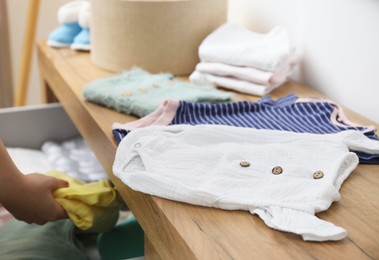 Photo of Woman with baby clothes at home, closeup