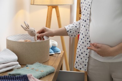 Photo of Pregnant woman with baby rattle at home, closeup