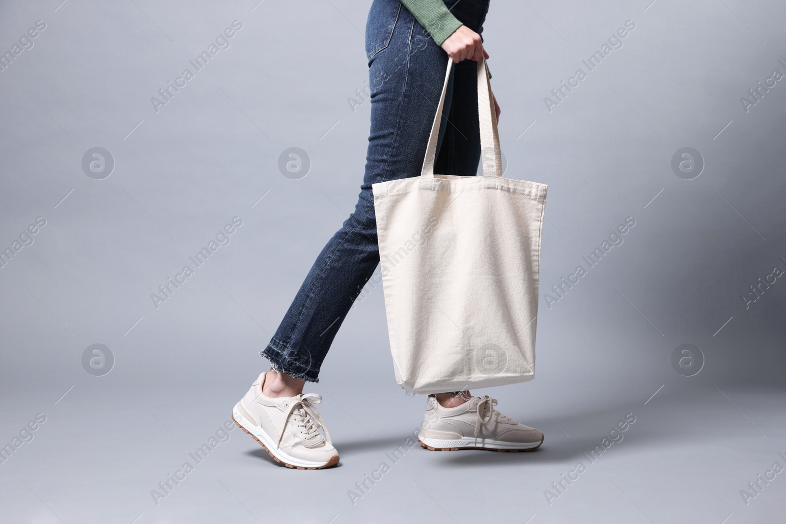 Photo of Woman with blank shopper bag on grey background, closeup. Mockup for design