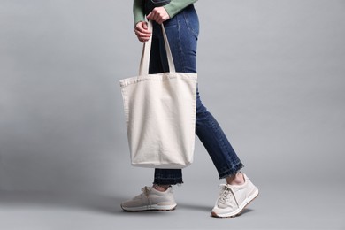 Photo of Woman with blank shopper bag on grey background, closeup. Mockup for design