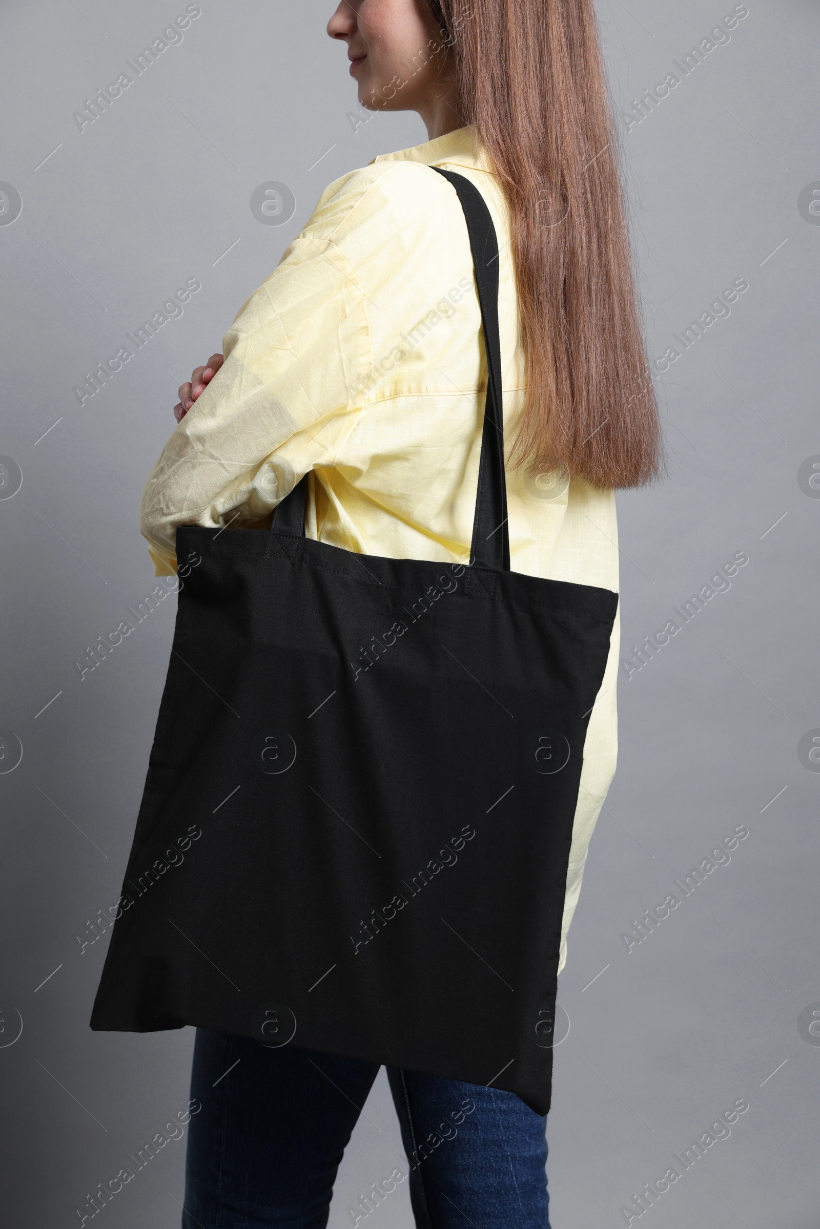 Photo of Woman with blank shopper bag on grey background, closeup. Mockup for design