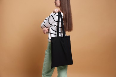 Photo of Woman with blank shopper bag on beige background, closeup. Mockup for design